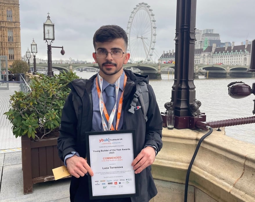 Luca holding his certificate infront at the House of Commons.